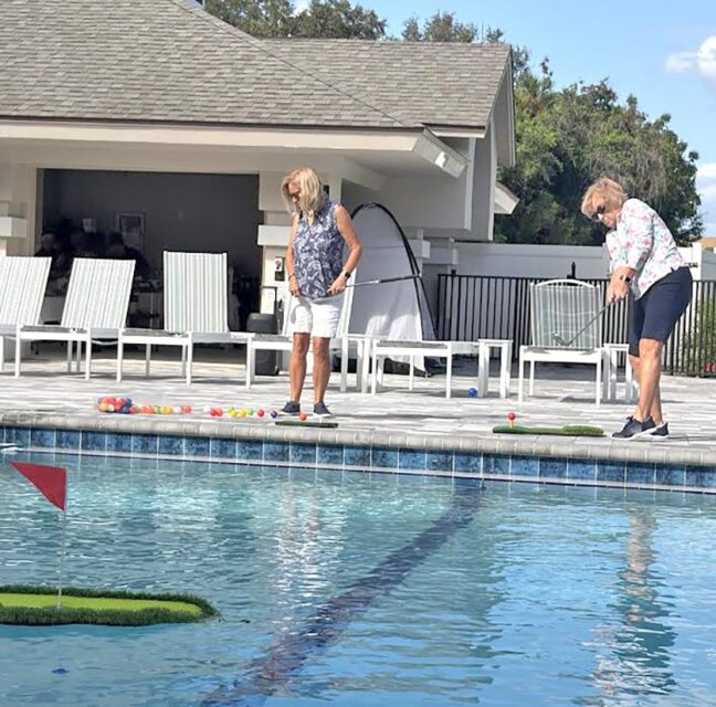 Two residents chipping toward the floating green beside the VCC pool