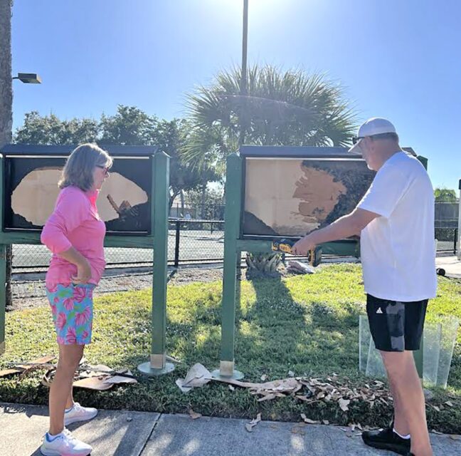 Volunteers scraping and cleaning community sign boards on Community Serve Day