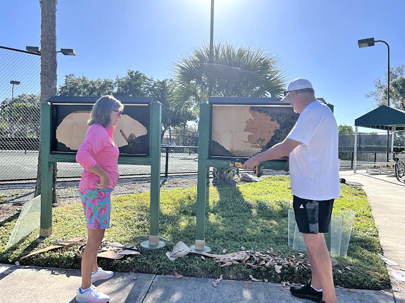 Volunteers scraping and cleaning community sign boards on Community Serve Day